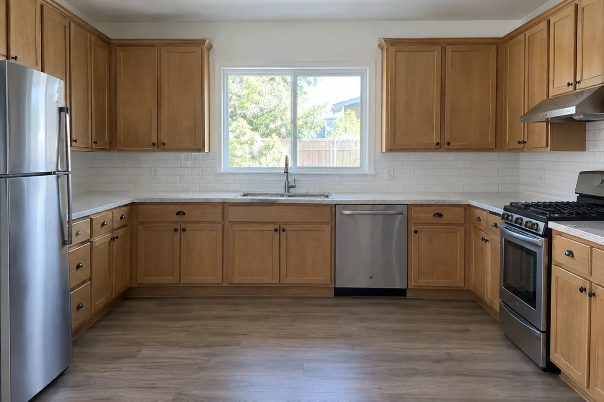A plain finished kitchen in an ordinary house with wood cabinets and no styling on the counters